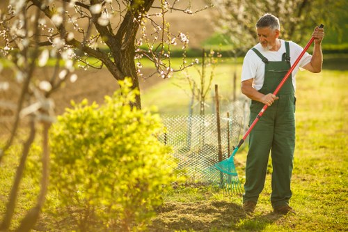 Gardener pruning shrubs and trees in a well-kept Ashburton garden